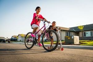 Self-Help Enterprises_Children riding bikes in community where parents built new and safe home 2014